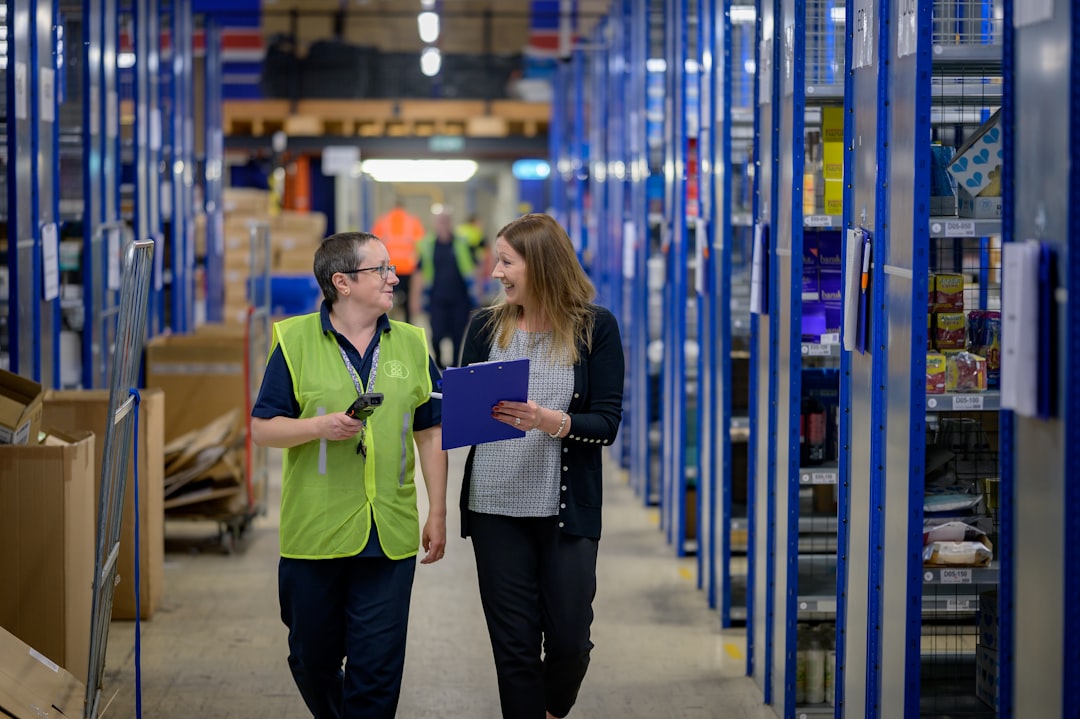 Two people walking through a warehouse with a clipboard, checking stock