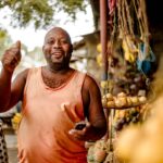 Market vendor holding a phone at her stall